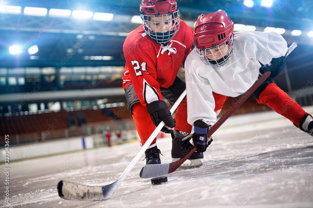Obraz premium children hockey player handling puck on ice.