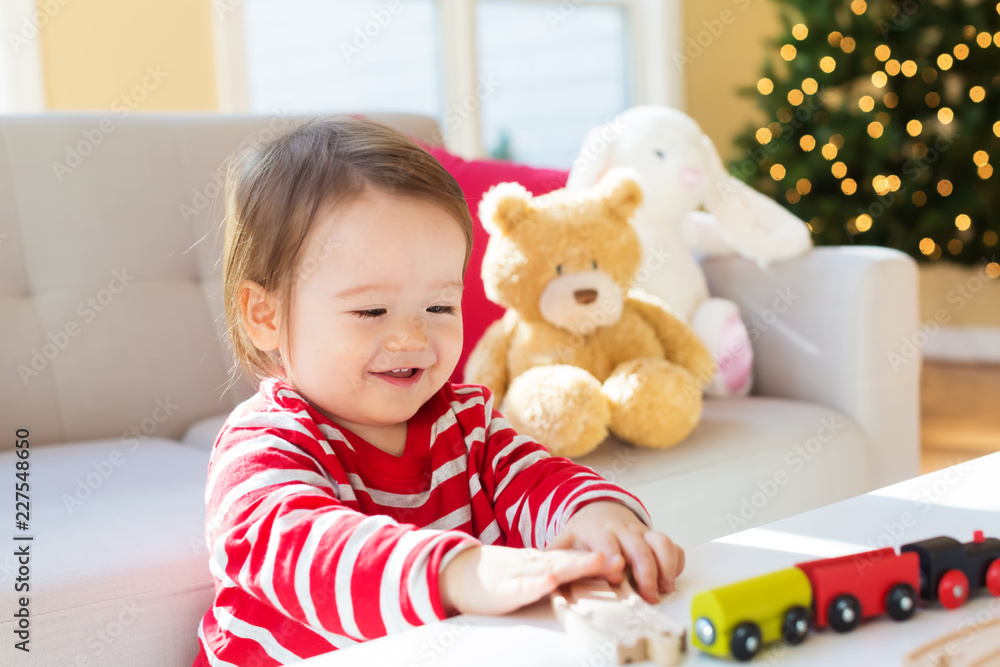 Happy toddler boy playing with toy trains on Christmas Happy toddler boy playing with toy trains on Christmas