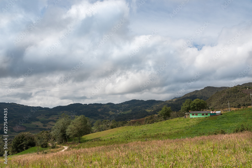 Farm house between hills and dirt road. Colombia.