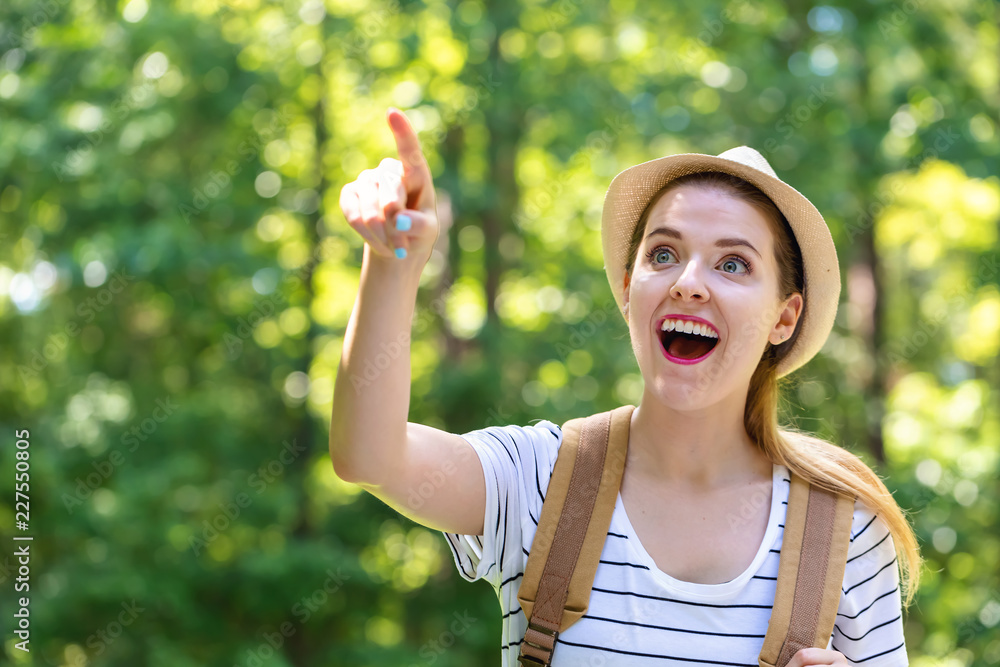 Young woman pointing while hiking on a bright summer day in the forest