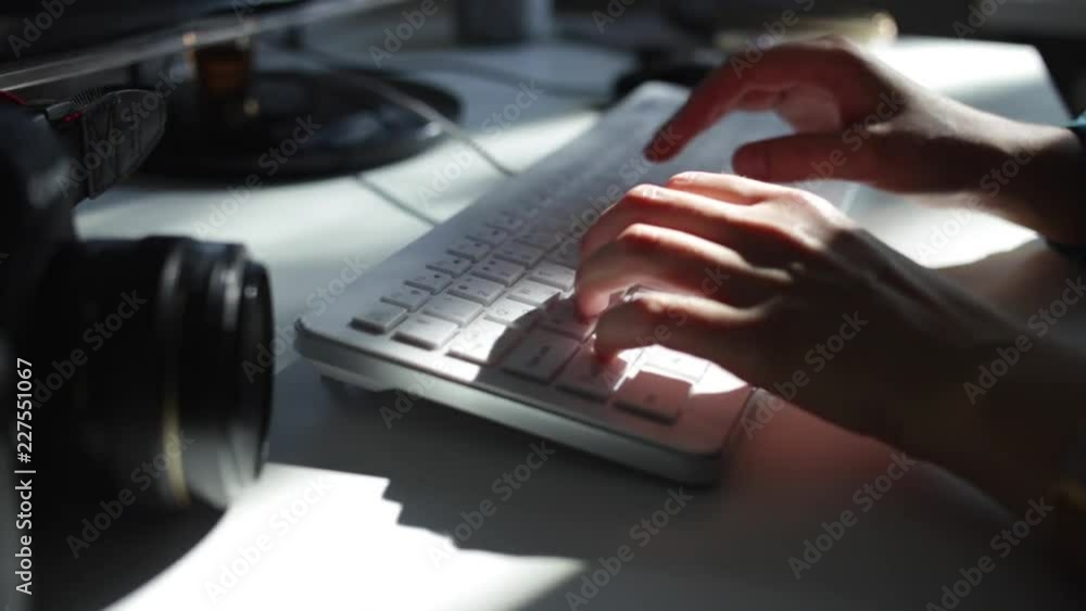 A close-up of female hands typing on a white keyboard. The play of sunlight A close-up of female hands typing on a white keyboard. The play of sunlight