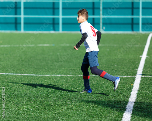 football teams - boys in red, blue, white uniform play soccer on the green field. boys dribbling. dribbling skills. Team game, training, active lifestyle, hobby, sport for kids concept