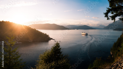 A ferry ship cruising out of a harbour in a mountain pass at sunset photo