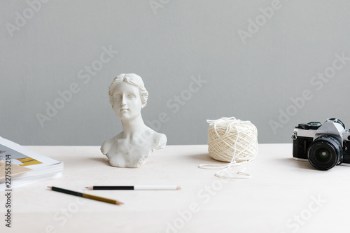 artist's desk with statue of woman, yarn and camera photo