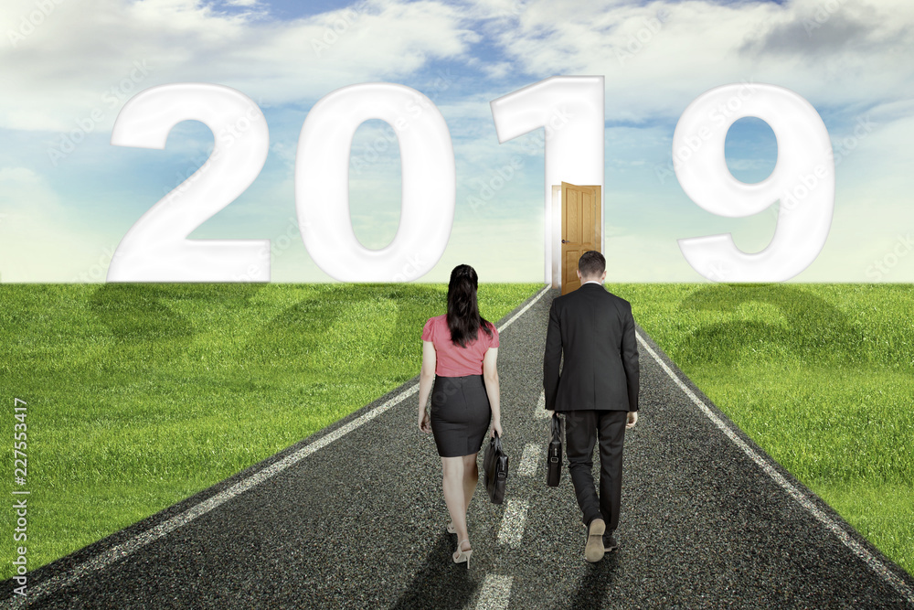 Business couple walks to door and number 2019 Business couple walks to door and number 2019