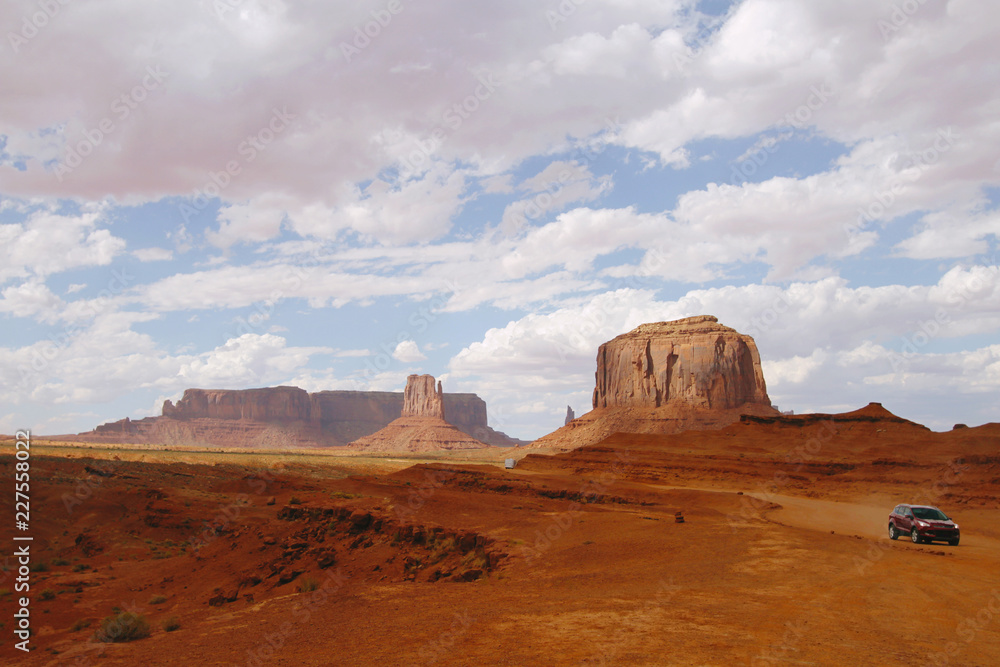 Pink-hued clouds traveling above Monument Valley's characteristic, iconic butte landscape. Pink-hued clouds traveling above Monument Valley's characteristic, iconic butte landscape.