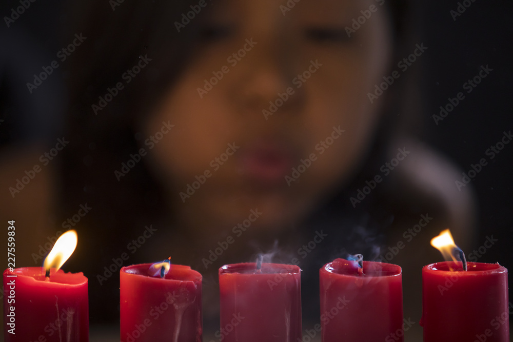 Little girl blowing five burning candles