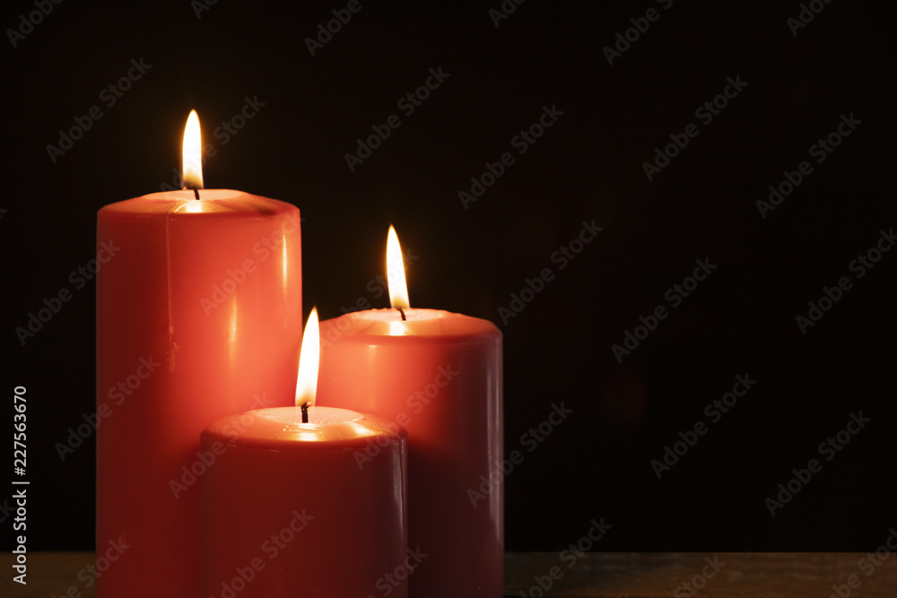 Three burning candles with dark background