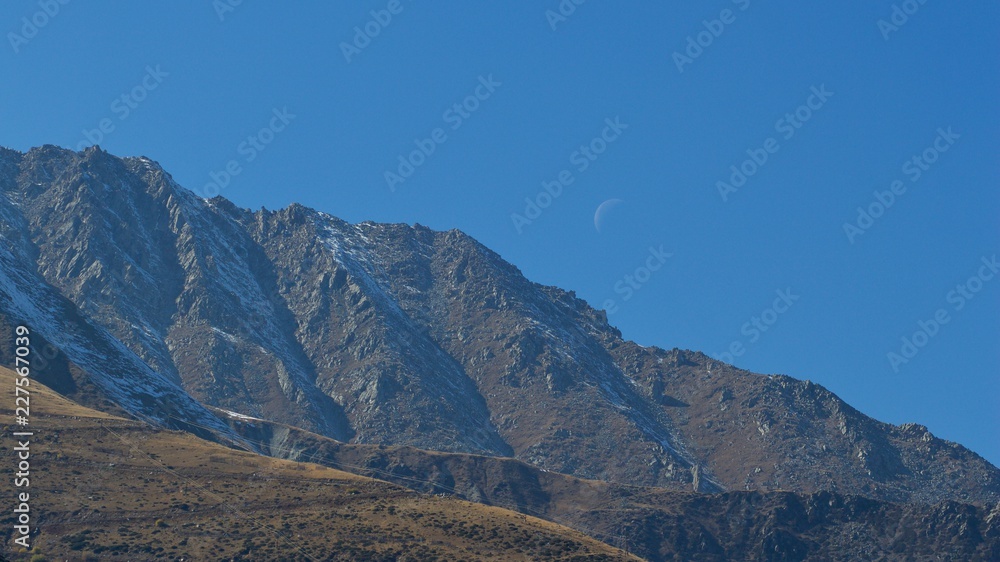 Dark Mountain and Clear Blue Sky near Almaty, Kazakhstan with Daytime Crescent Moon