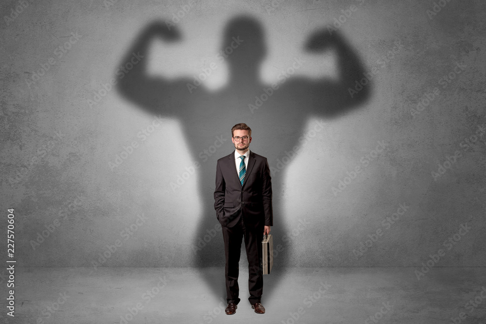 Obraz premium Lovely serious businessman standing with a muscular powerful shadow behind his back 