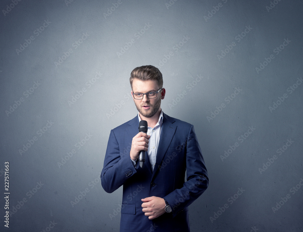 Businessman speaking into microphone with blue background Businessman speaking into microphone with blue background