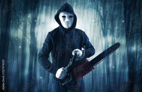 Masked armed hitman in dark thick forest with foggy mysterious concept 