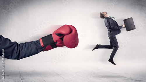 Huge Boxing Gloves punches innocent businessman concept
