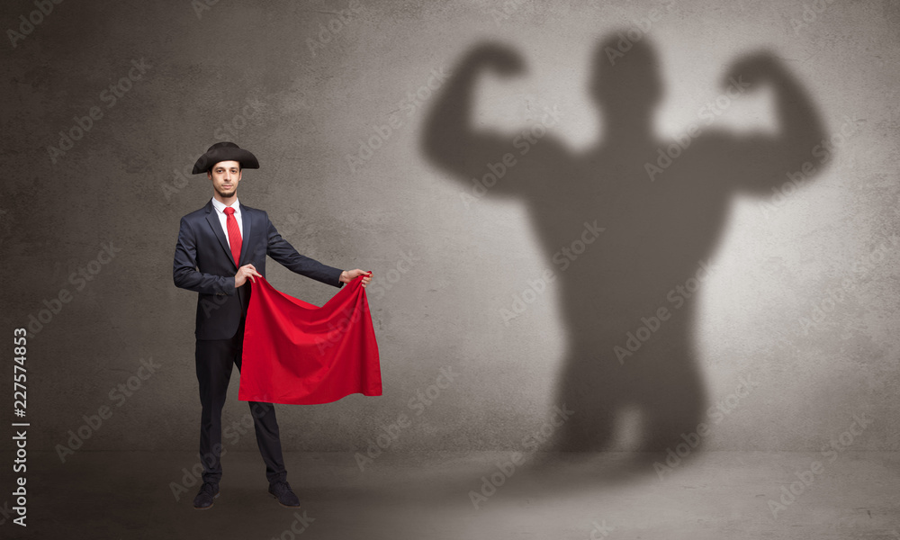 Fototapeta premium Businessman standing with red cloth on his hand and strong hero shadow on the background 