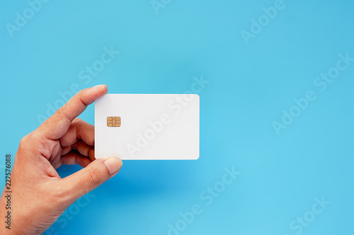 Hand holding blank credit chip card on blue background for business and finance concept