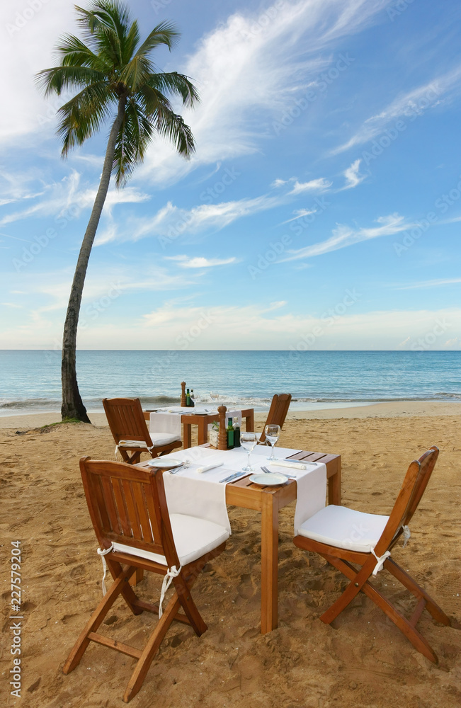 Outside dining setup on a tropical beach with palm tree