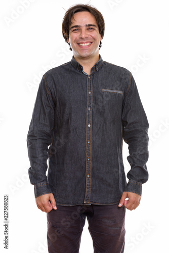 Studio shot of young happy Persian man smiling and standing