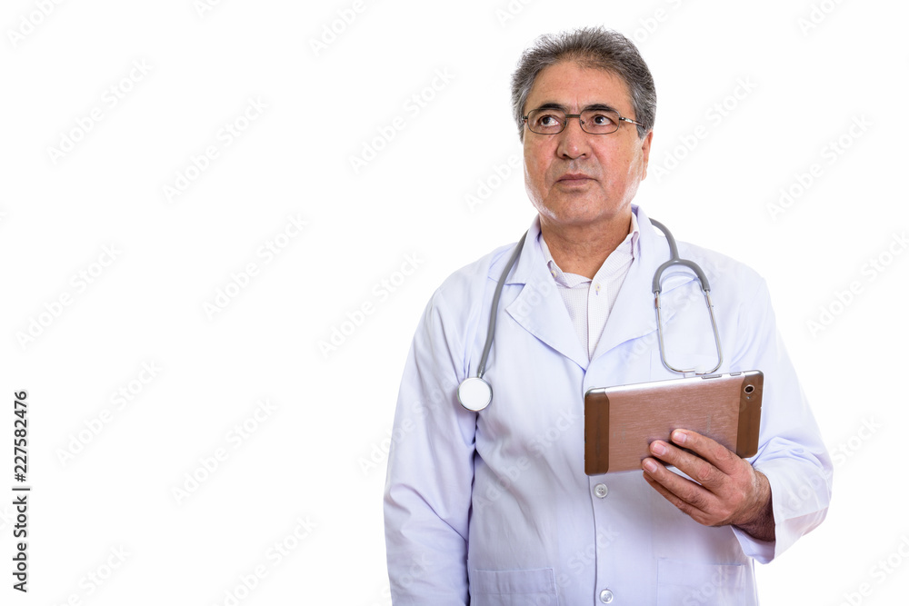 Studio shot of senior Persian man doctor holding digital tablet Studio shot of senior Persian man doctor holding digital tablet