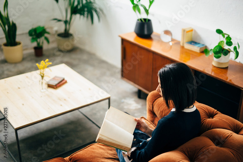 Girl reading on a orange velvet chester sofa