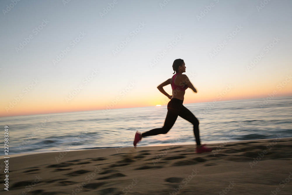 Fit woman running and working out on the beach at sunset Fit woman running and working out on the beach at sunset