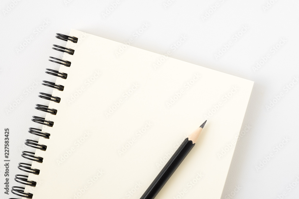 Top view of open spiral blank notebook with pencil on white desk background Top view of open spiral blank notebook with pencil on white desk background