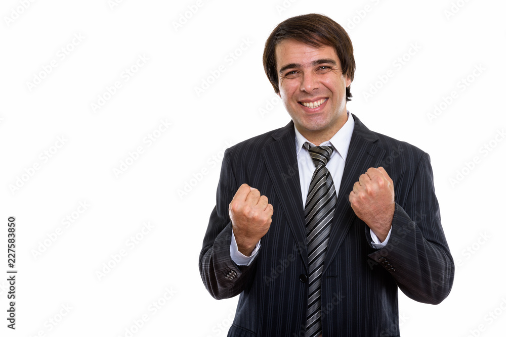 Studio shot of young happy Persian businessman smiling while loo Studio shot of young happy Persian businessman smiling while loo