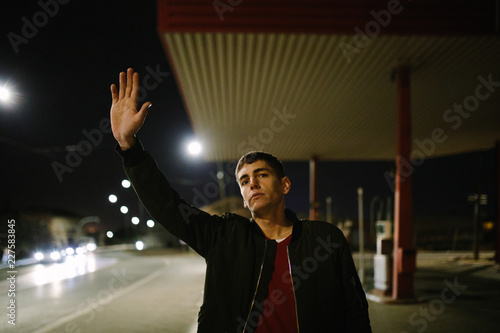 Man hitchhiking on road in night