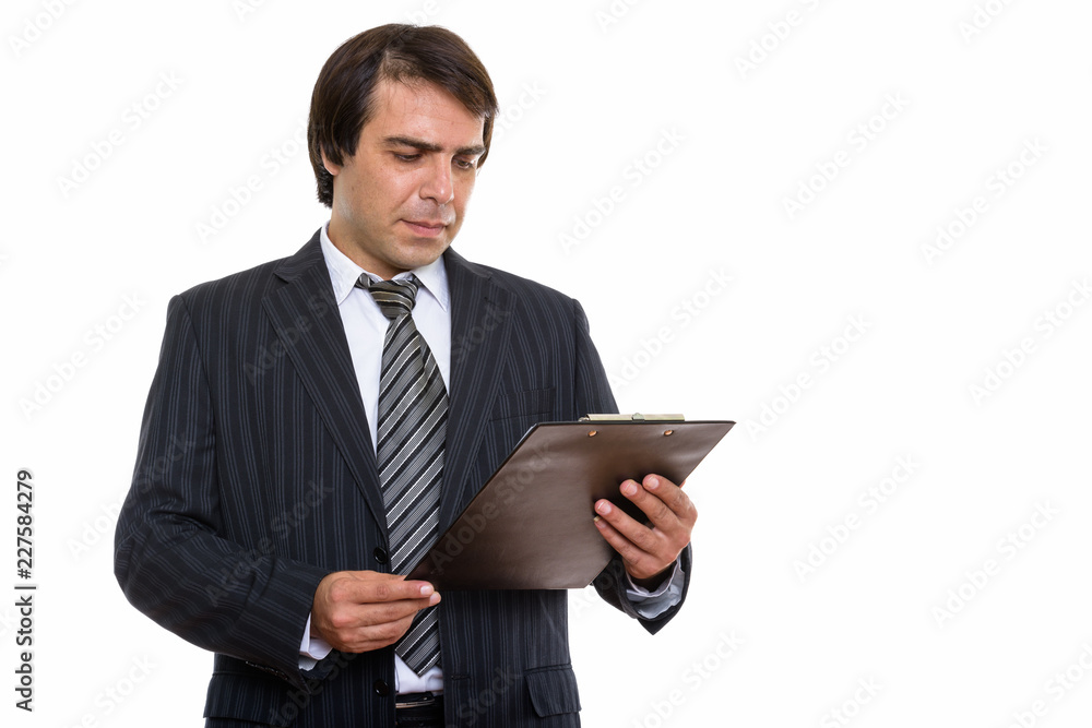 Studio shot of young Persian businessman reading on clipboard Studio shot of young Persian businessman reading on clipboard