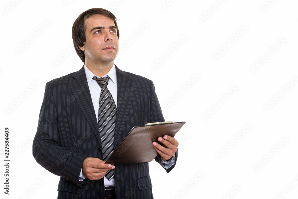 Studio shot of young Persian businessman holding clipboard while Studio shot of young Persian businessman holding clipboard while