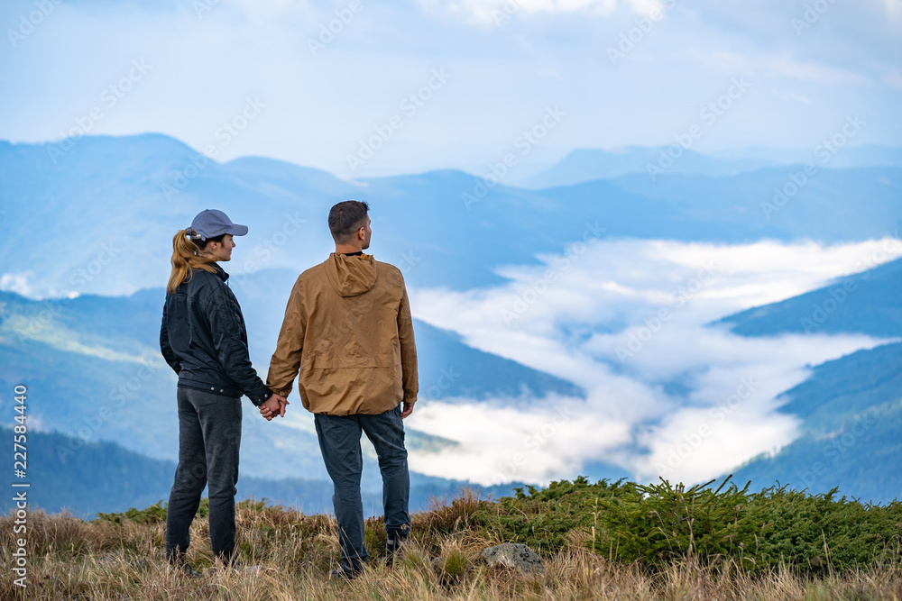 The man and a woman standing on the mountain landscape background