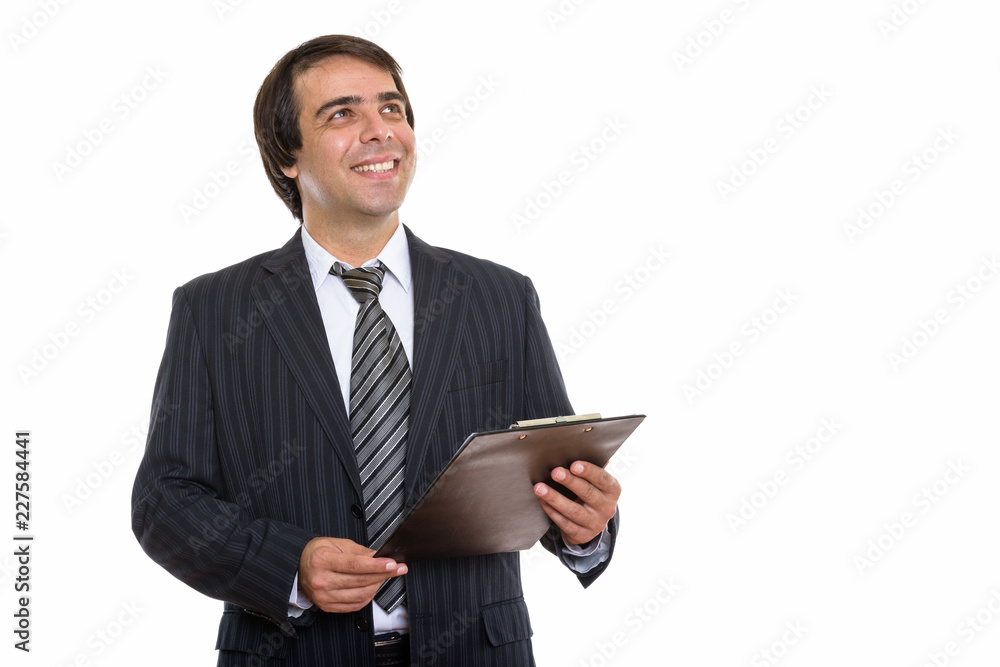 Studio shot of young happy Persian businessman smiling and holdi Studio shot of young happy Persian businessman smiling and holdi