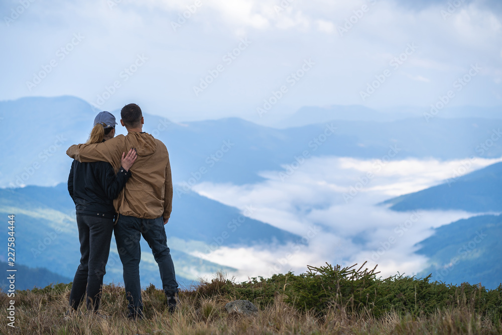 The man and a woman standing on the mountain landscape background The man and a woman standing on the mountain landscape background