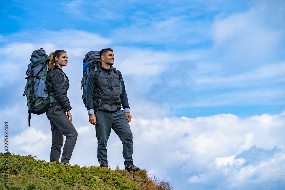The man and a woman with backpacks standing on the mountain landscape background