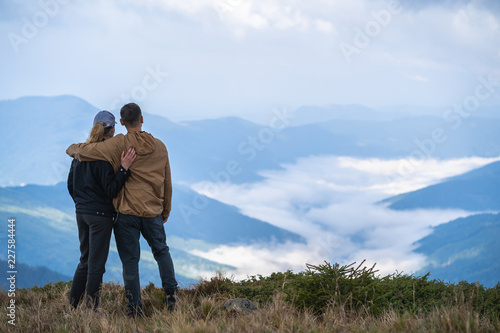 The man and a woman standing on the mountain landscape background