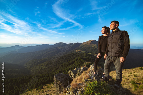 The smiling couple standing on the beautiful mountain landscape background