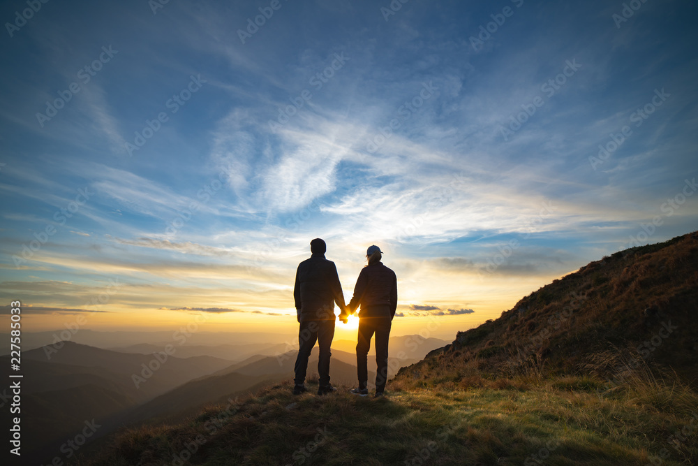 The couple standing on the rock with a picturesque sunrise