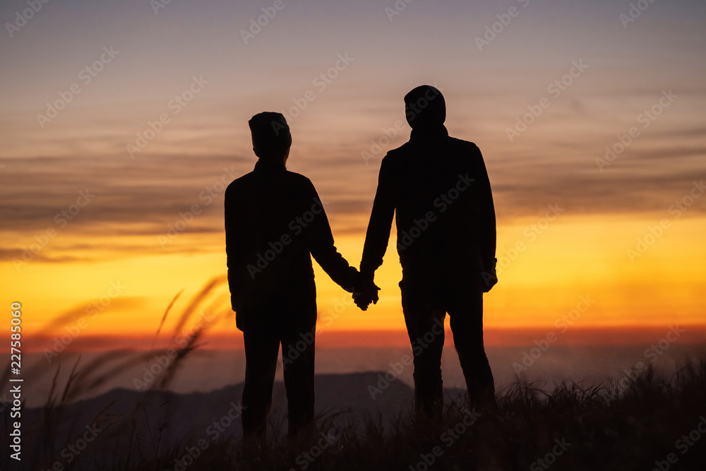 The couple on the mountain enjoying a picturesque sunset background