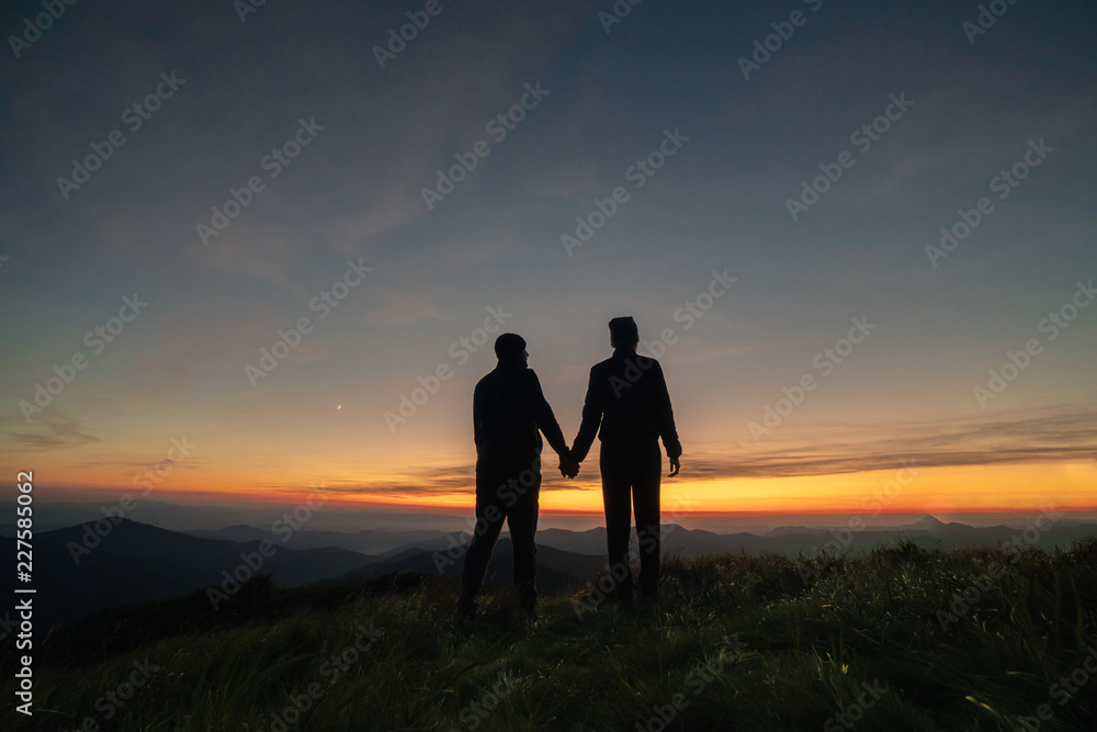The silhouette of the couple on the mountain sunset background
