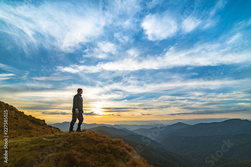 The man standing on the rock with a picturesque sunset