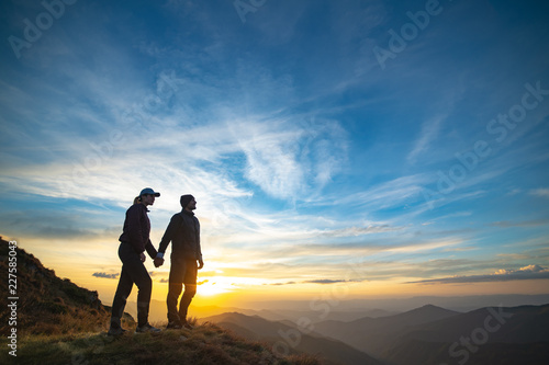 The couple standing on the rock with a picturesque sunrise