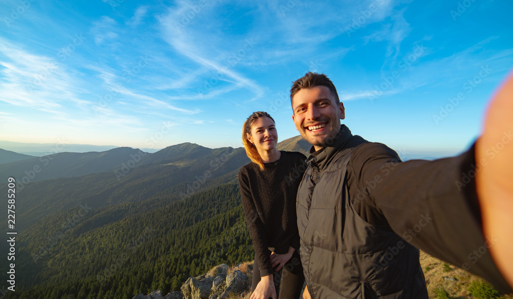 The beautiful couple taking a selfie on the mountain background