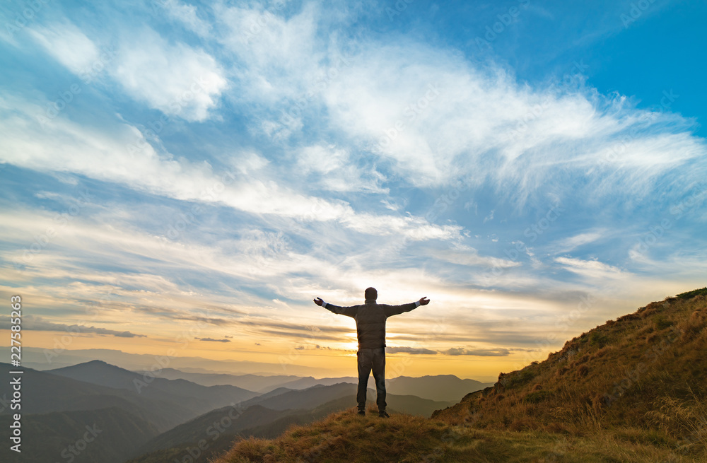 The happy man standing on the rock with a picturesque sunset