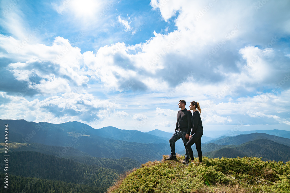 The happy couple standing on the mountain with a picturesque cloudscape The happy couple standing on the mountain with a picturesque cloudscape