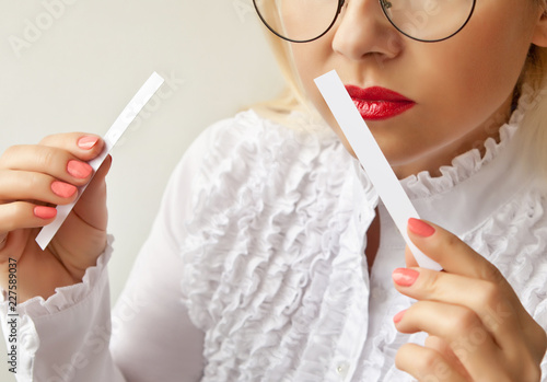 A woman with paper strips in her hands listens to the fragrance.
