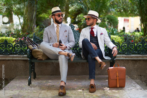 Two stylish men with suits, hats and sunglasses