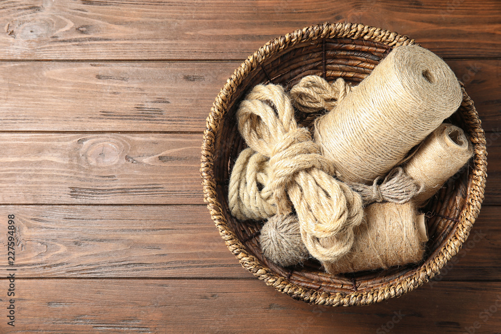 Natural hemp ropes in wicker basket on wooden background, top view with space for text Natural hemp ropes in wicker basket on wooden background, top view with space for text