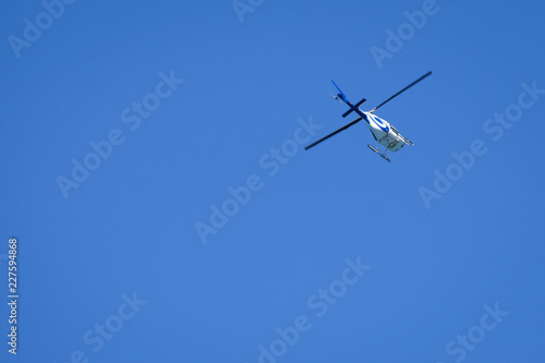 Helicopter in flight from below against blue sky. Add your own text.