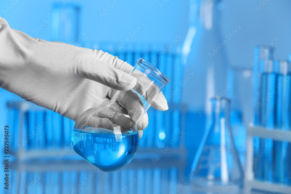 Scientist holding test flask with sample in laboratory. Chemical analysis Scientist holding test flask with sample in laboratory. Chemical analysis