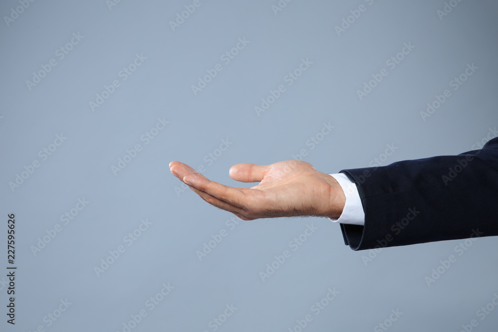 Businessman holding something on grey background, closeup view of hand with space for text Businessman holding something on grey background, closeup view of hand with space for text