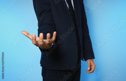 Businessman holding something on color background, closeup of hands